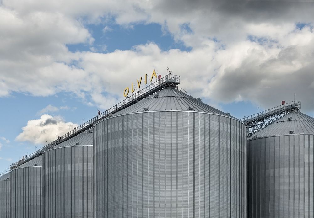 Силоси елеватора зі знаком OLVIA на тлі хмар