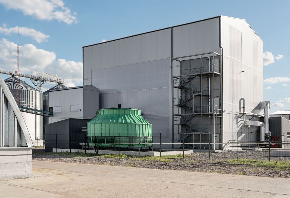 Виробничий корпус із зовнішніми сходовими маршами, градирня охолодження, позаду силоси елеватора